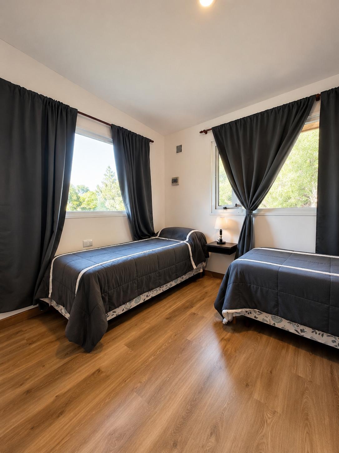 Habitación de cabaña con dos camas individuales, piso de madera y mucha luz natural